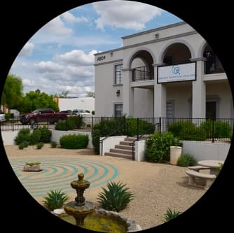 Exterior of the Clear Quantum Healing building with arched entryways and a desert-style front garden featuring a labyrinth and fountain.