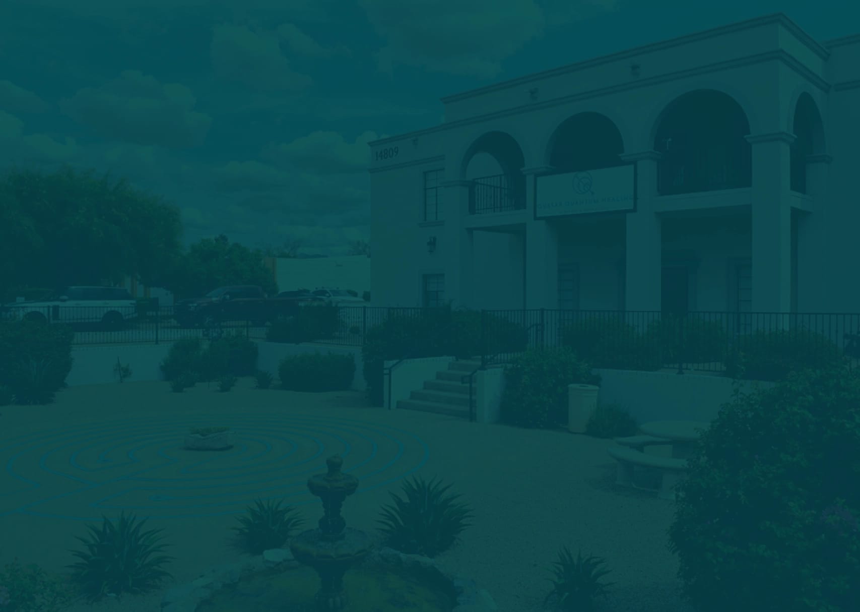 A building displaying '14809' and 'Quantum Healing' with a courtyard featuring a labyrinth pattern and fountain in the foreground.